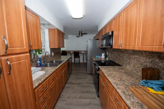 a kitchen with stainless steel appliances granite countertop a stove a sink dishwasher and cabinets with wooden floor