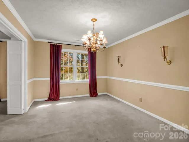 a view of a livingroom with a chandelier curtains and large windows