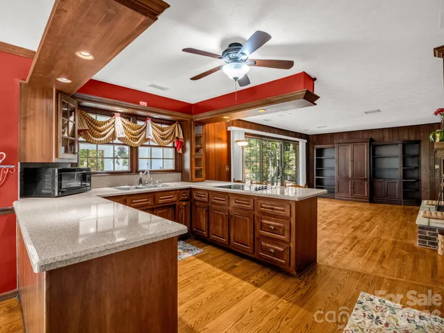 a large kitchen with stainless steel appliances granite countertop a sink and wooden cabinets