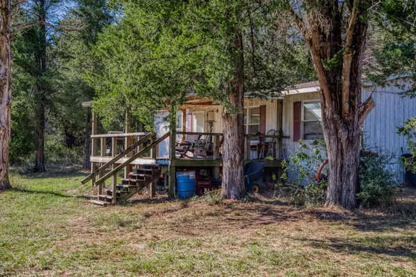 a view of a wooden deck and a yard with large trees