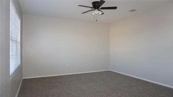 an empty room with a window and a fan