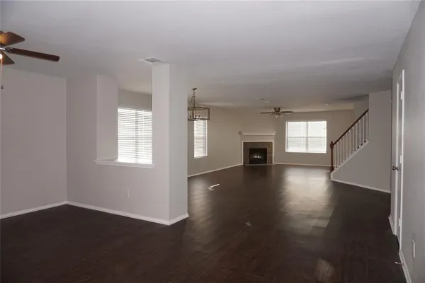 an empty room with wooden floor fireplace and windows