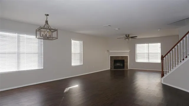 an empty room with wooden floor fireplace and windows