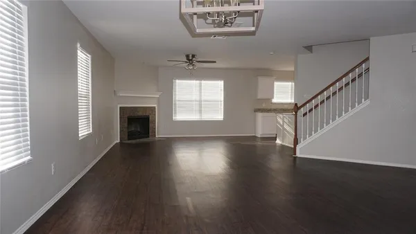 an empty room with wooden floor fireplace and windows