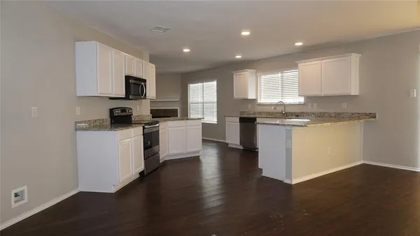 a kitchen with stainless steel appliances granite countertop a stove top oven a sink a window and white cabinets