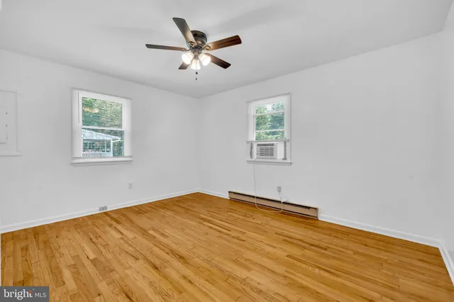 a view of empty room with wooden floor and fan