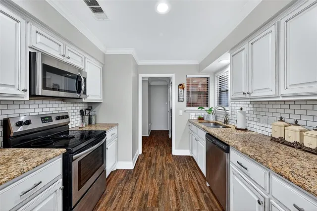 a kitchen with granite countertop wooden cabinets stove top oven and sink