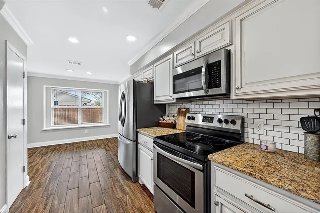 a kitchen with granite countertop wooden cabinets stove and microwave