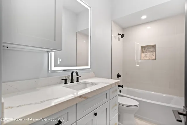 a bathroom with a granite countertop sink a toilet and a bathtub