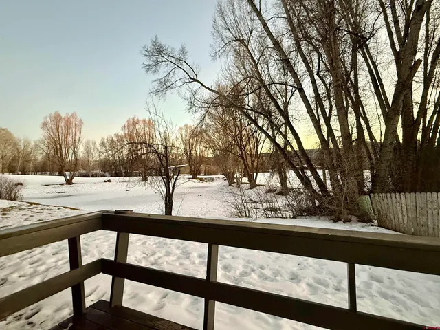 a view of trees and deck with wooden fence