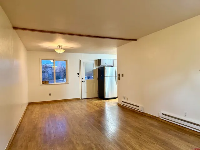 a view of an empty room with a window and wooden floor