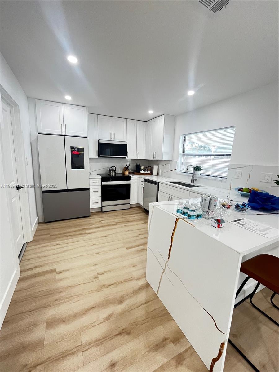 9703 Southwest 2nd Street Boca Raton, FL 33428 - Photo 1 of 17 a kitchen with kitchen island a white counter top space a refrigerator a stove a microwave and cabinets