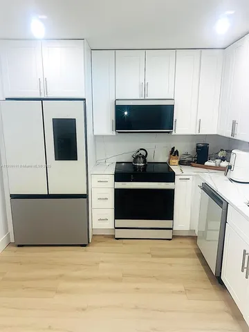 a kitchen with stainless steel appliances white cabinets and wooden floor