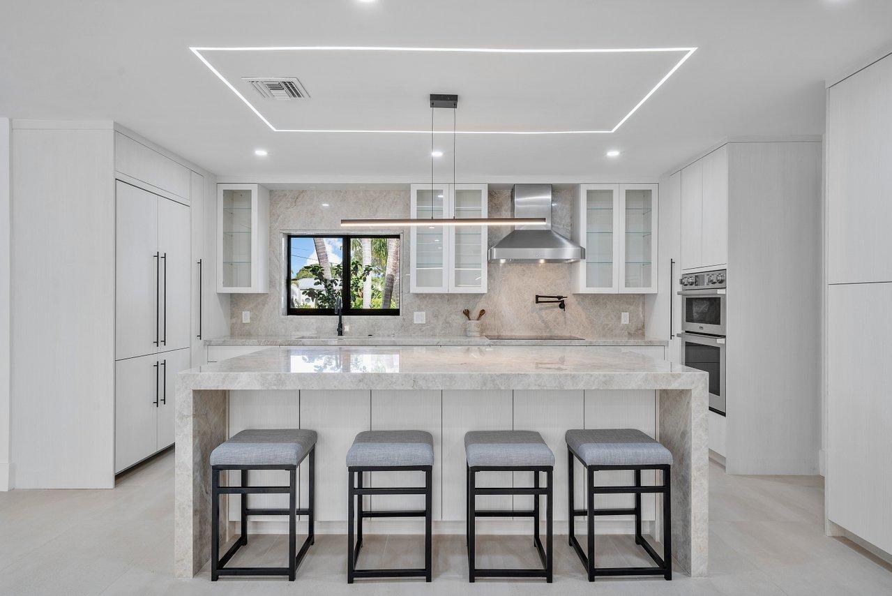 a large white kitchen with granite countertop a table and chairs in it