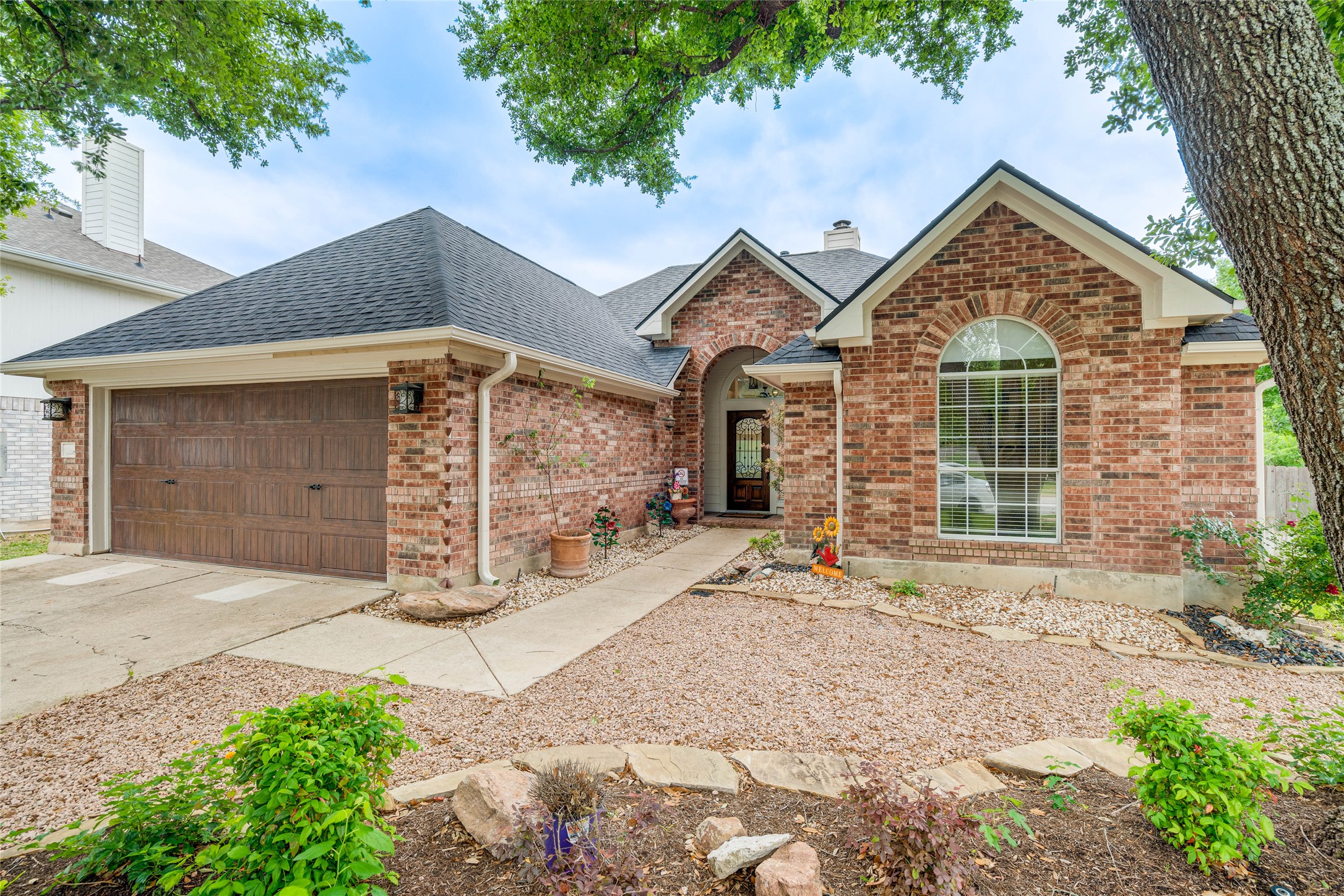 1209 Lacey Oak Loop Round Rock, TX 78681 - Photo 2 of 22 Brick exterior featuring a gabled roofline, arched entry, and an arched window