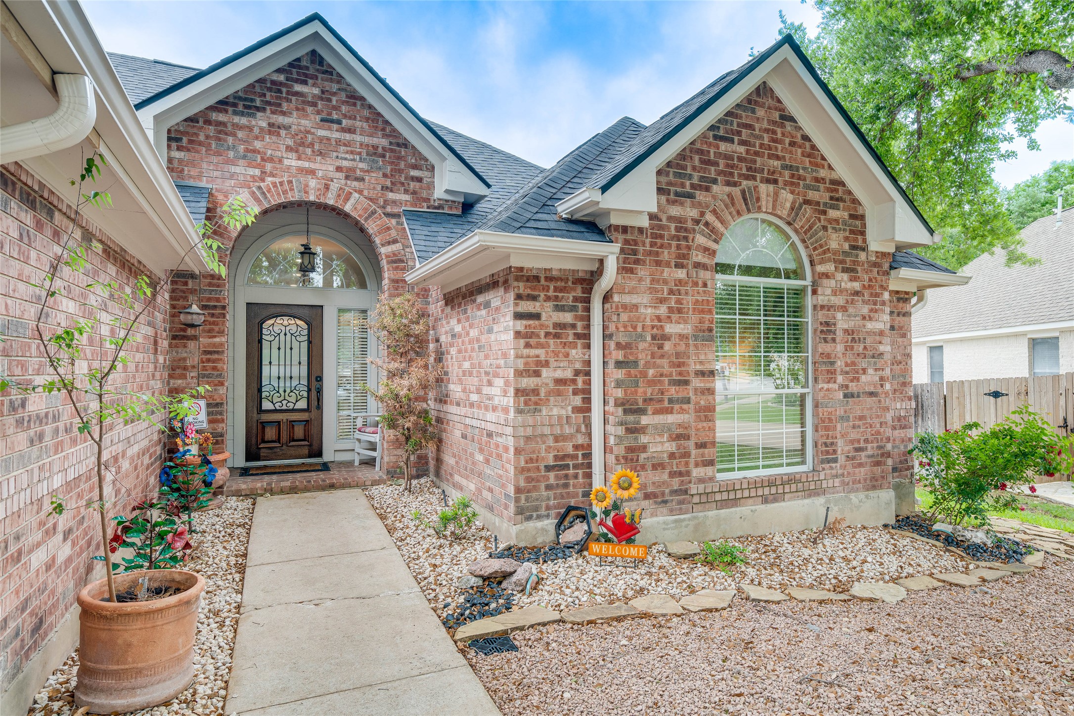 1209 Lacey Oak Loop Round Rock, TX 78681 - Photo 3 of 22 Brick exterior featuring gabled rooflines, arched entryway, and leaded glass front door