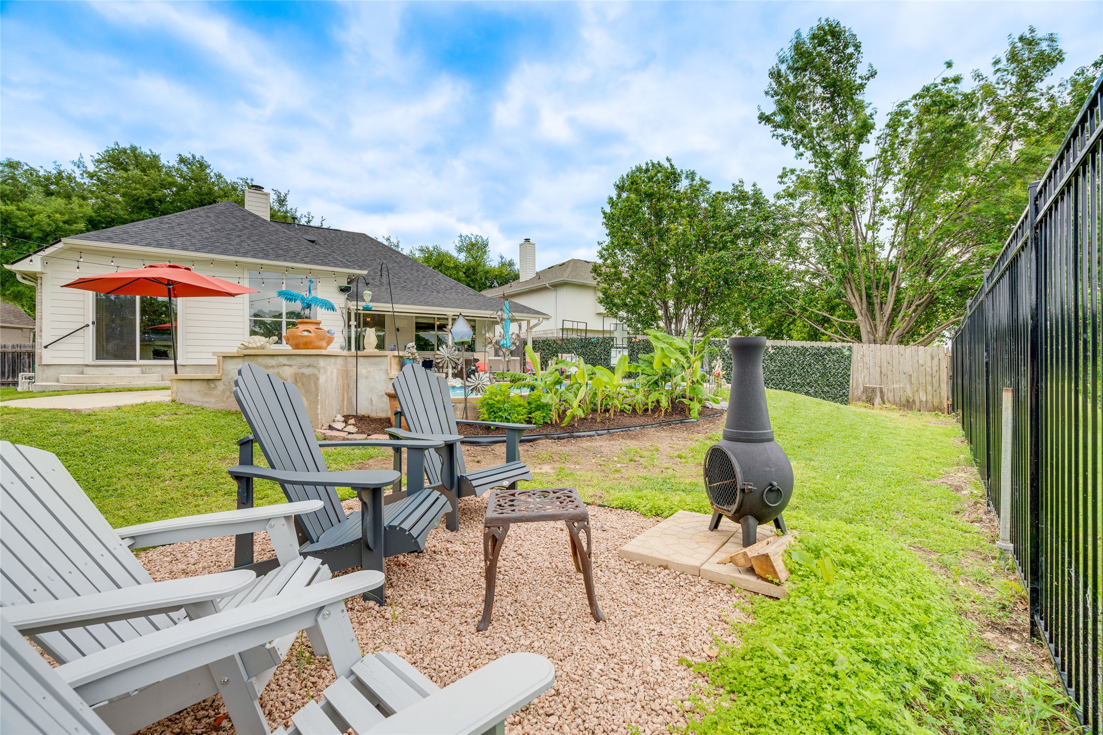 1209 Lacey Oak Loop Round Rock, TX 78681 - Photo 6 of 22 Spacious backyard featuring a sloped lawn, a gravel patio area with a built-in fire pit, and an established garden bed