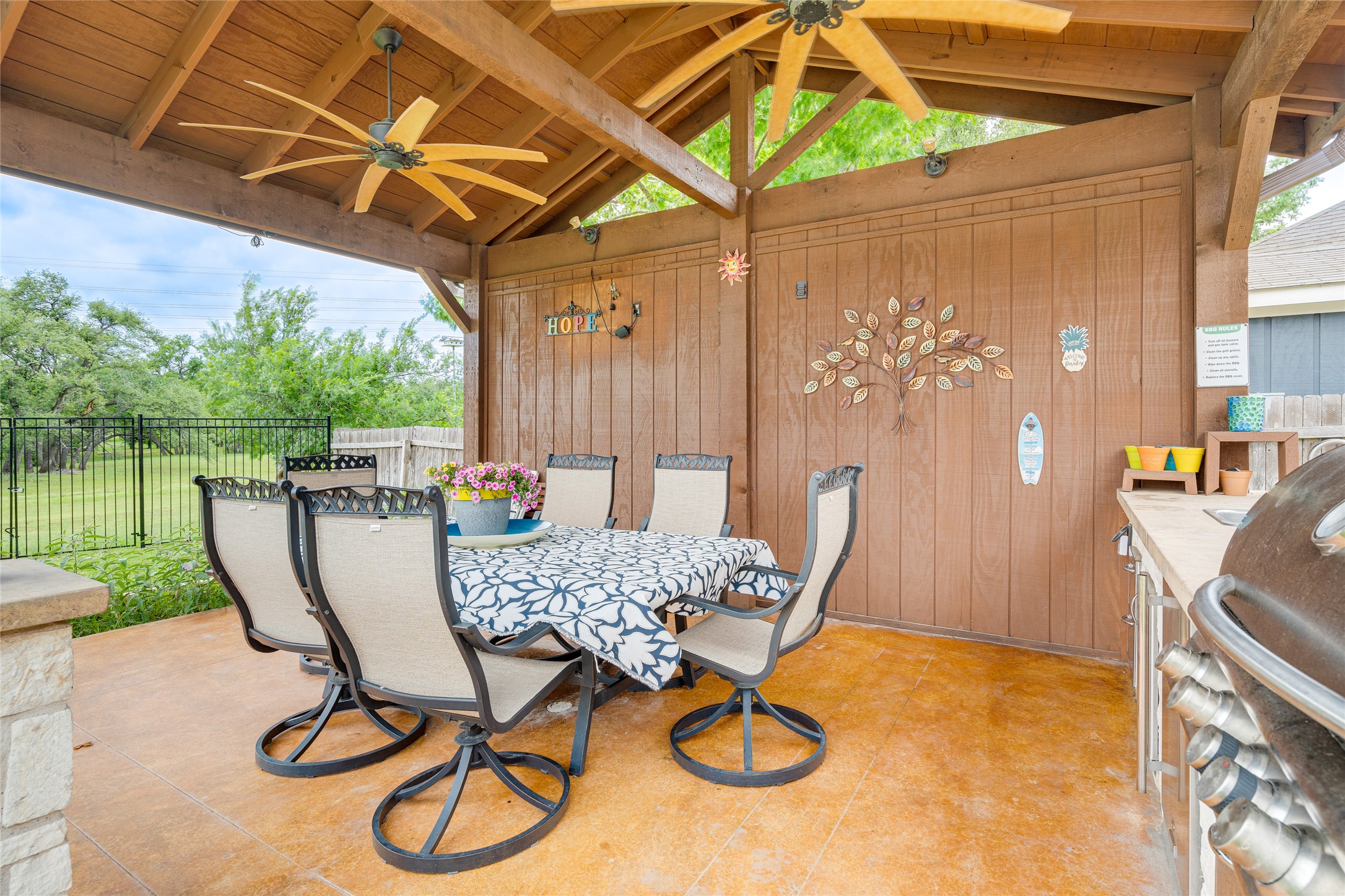 1209 Lacey Oak Loop Round Rock, TX 78681 - Photo 8 of 22 Covered outdoor living space featuring a wood-panel ceiling, multiple ceiling fans, stained concrete flooring, and a stone-clad half-wall
