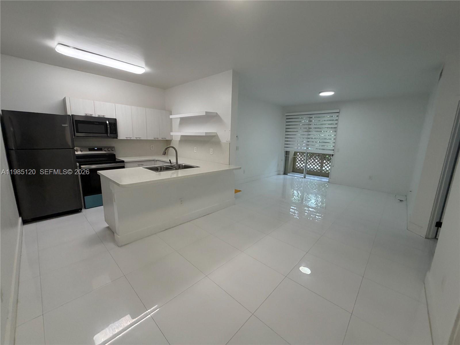 18328 Northwest 68th Avenue, Unit I Hialeah, FL 33015 - Photo 8 of 15 a kitchen with stainless steel appliances a refrigerator sink and stove