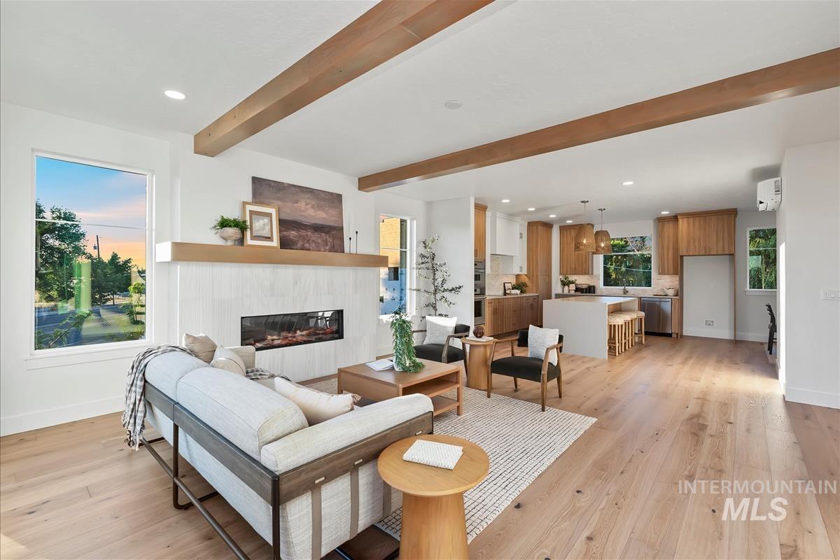 3219 West Moore Street Boise, ID 83702 - Photo 12 of 36 Bright living space featuring wood-finish flooring, a linear fireplace with a textured surround, and exposed ceiling beams