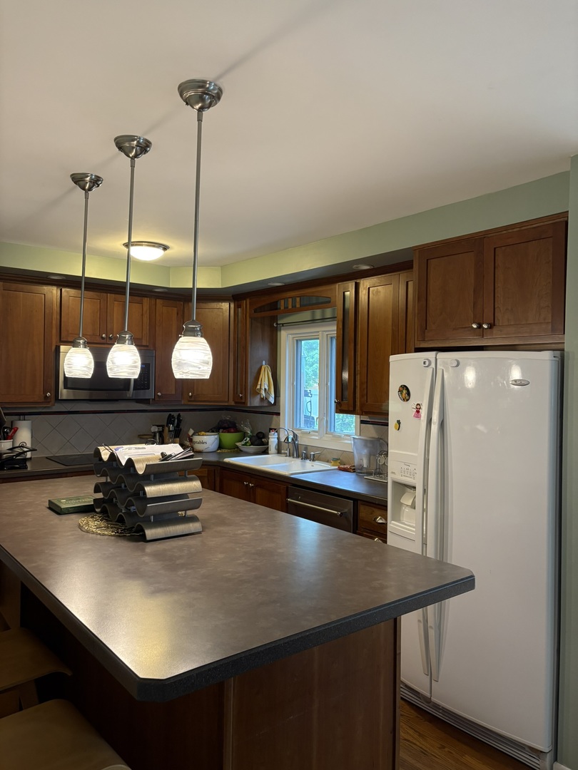 609 West Gartner Road Naperville, IL 60540 - Photo 5 of 23 a kitchen with a refrigerator a sink and chairs