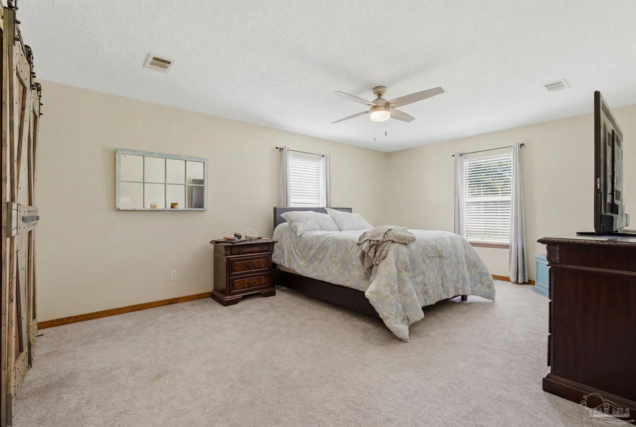6870 Martin Road Milton, FL 32570 - Photo 30 of 48 a spacious bedroom with a bed and a flat screen tv