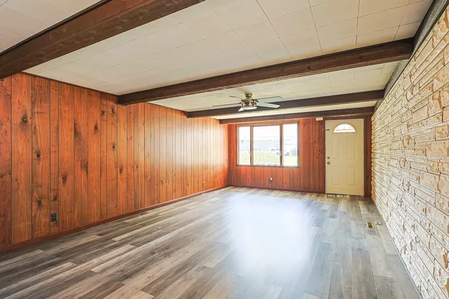 a view of an empty room with a window and wooden floor