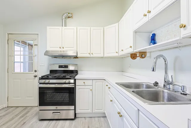 a kitchen with white cabinets sink and appliances
