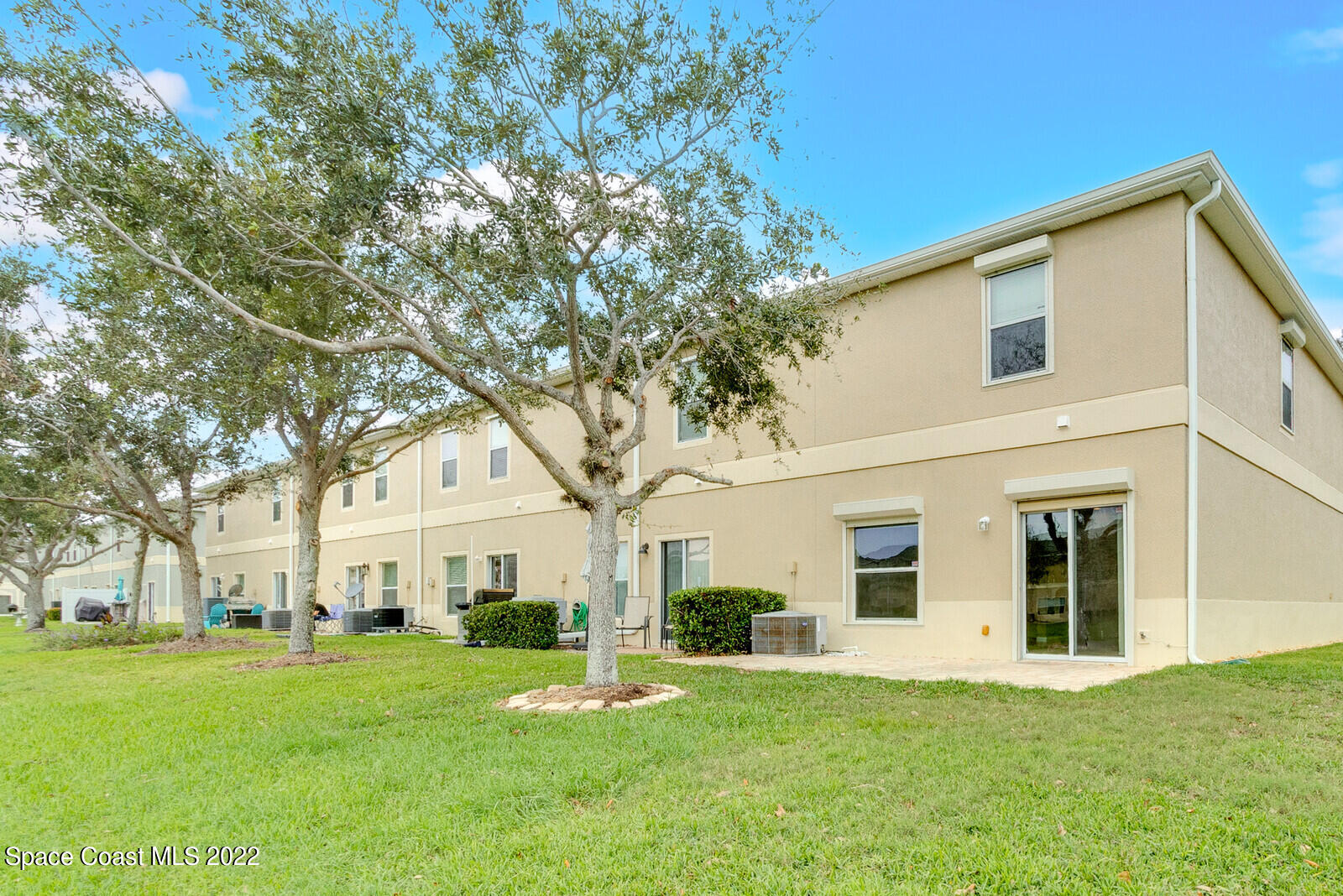 2765 Revolution Street, Unit 101 Melbourne, FL 32935 - Photo 31 of 48 a view of a white house with a big yard and large trees