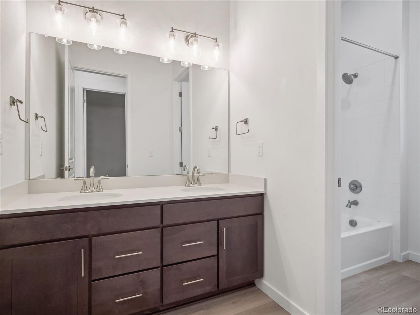 9178 Gold Lace Place Littleton, CO 80129 - Photo 4 of 26 a bathroom with a double vanity sink and mirror with shower