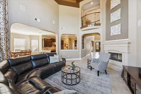 a living room with couches a fireplace and kitchen view with wooden floor
