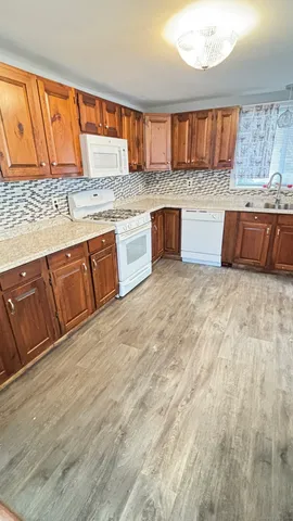 a kitchen with stainless steel appliances granite countertop a sink dishwasher stove and wooden cabinets