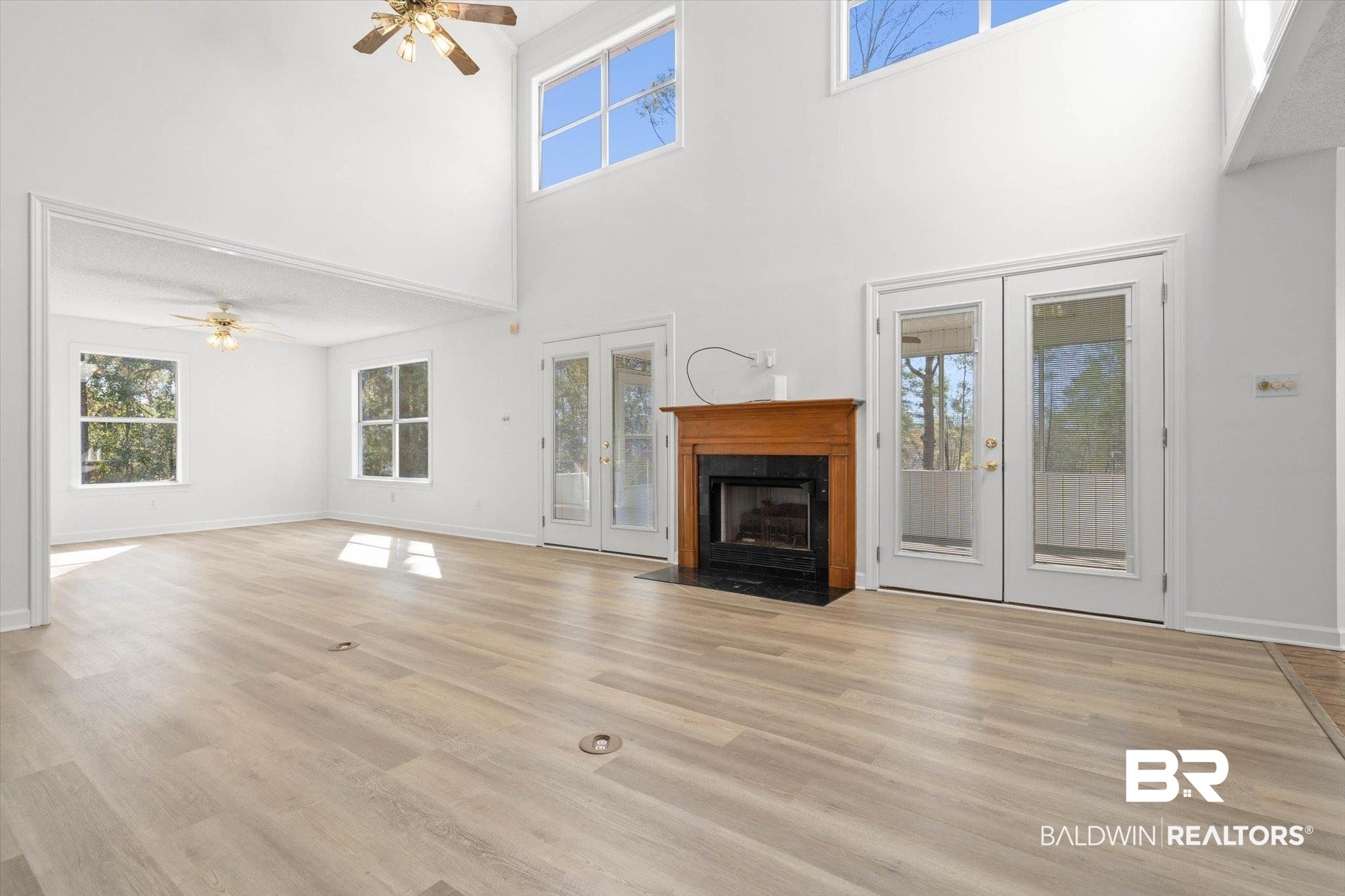 3847 Riviere Du Chien Road Mobile, AL 36693 - Photo 11 of 51 Unfurnished living room with french doors, a ceiling fan, a fireplace with flush hearth, plenty of natural light, and a high ceiling