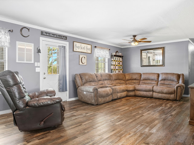 30063 South 4300th Road Stigler, OK 74462 - Photo 15 of 58 Wood-finish flooring throughout, ceiling fan with integrated lighting, white crown molding, and a white paneled door with glass insert