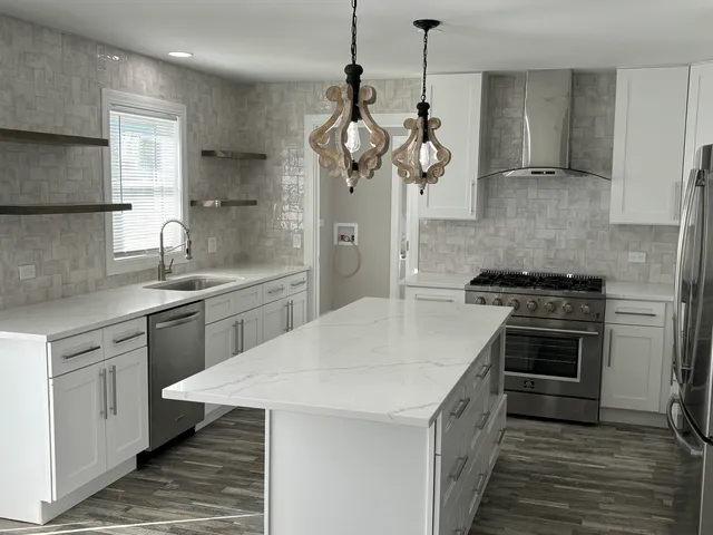 a kitchen with stainless steel appliances kitchen island a refrigerator sink and wooden floor