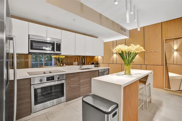 a kitchen that has a lot of white cabinets and stainless steel appliances