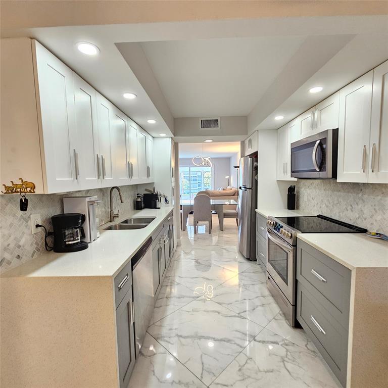 1705 Andros Isle, Unit C3 Coconut Creek, FL 33066 - Photo 2 of 36 a kitchen with stainless steel appliances granite countertop a stove a sink a microwave and a refrigerator