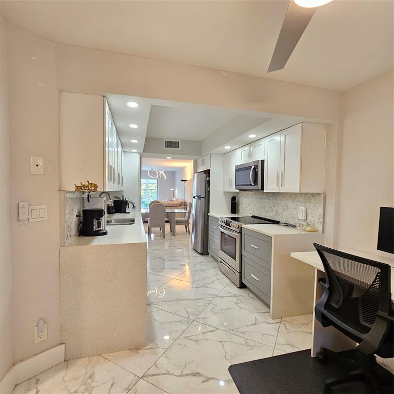 1705 Andros Isle, Unit C3 Coconut Creek, FL 33066 - Photo 23 of 36 a kitchen with stainless steel appliances granite countertop a stove top oven a sink a dining table and chairs