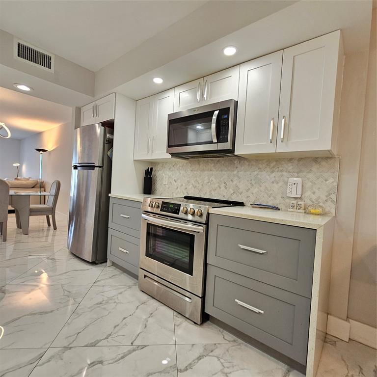 1705 Andros Isle, Unit C3 Coconut Creek, FL 33066 - Photo 24 of 36 a kitchen with stainless steel appliances granite countertop a refrigerator and a stove top oven