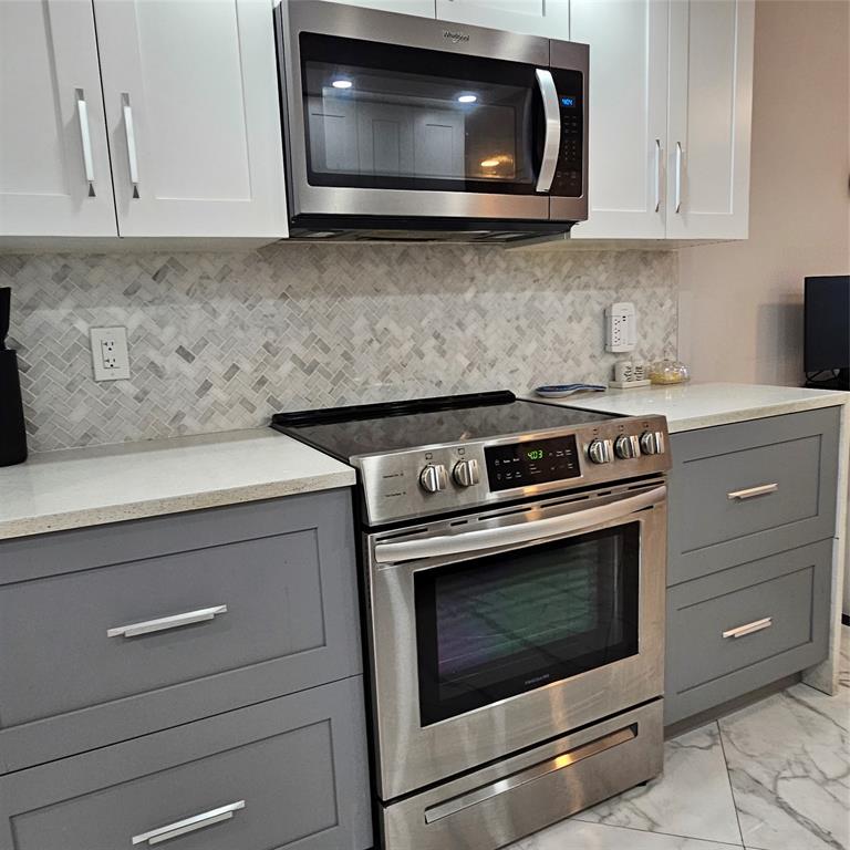 1705 Andros Isle, Unit C3 Coconut Creek, FL 33066 - Photo 26 of 36 a kitchen with microwave cabinets and stove top oven