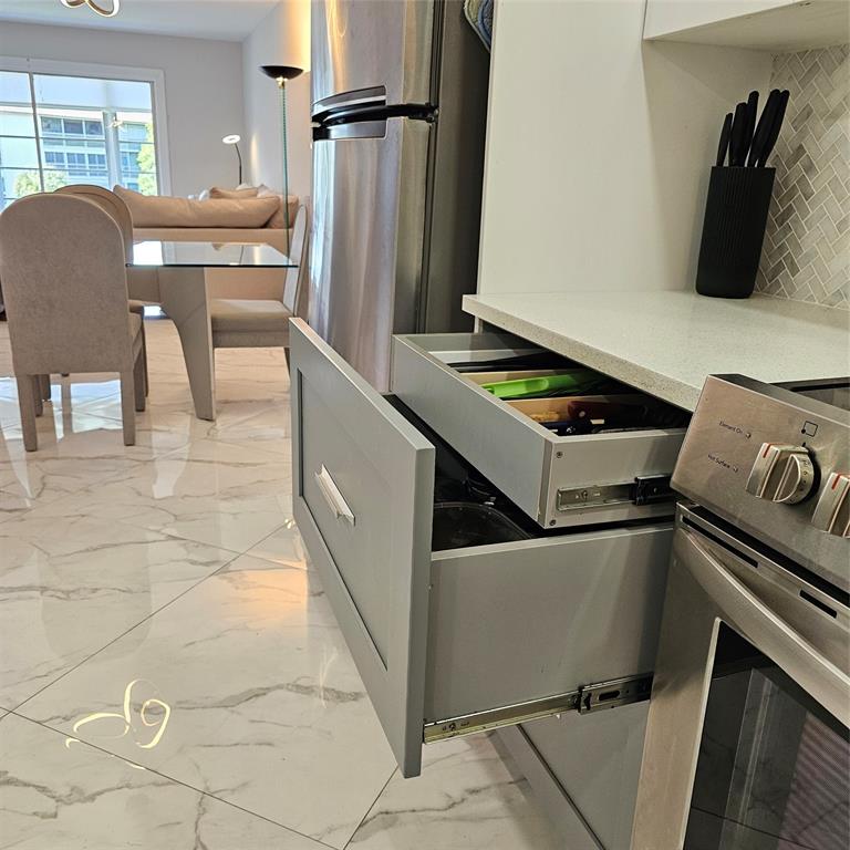 1705 Andros Isle, Unit C3 Coconut Creek, FL 33066 - Photo 27 of 36 a kitchen with a stove a refrigerator and a dining table