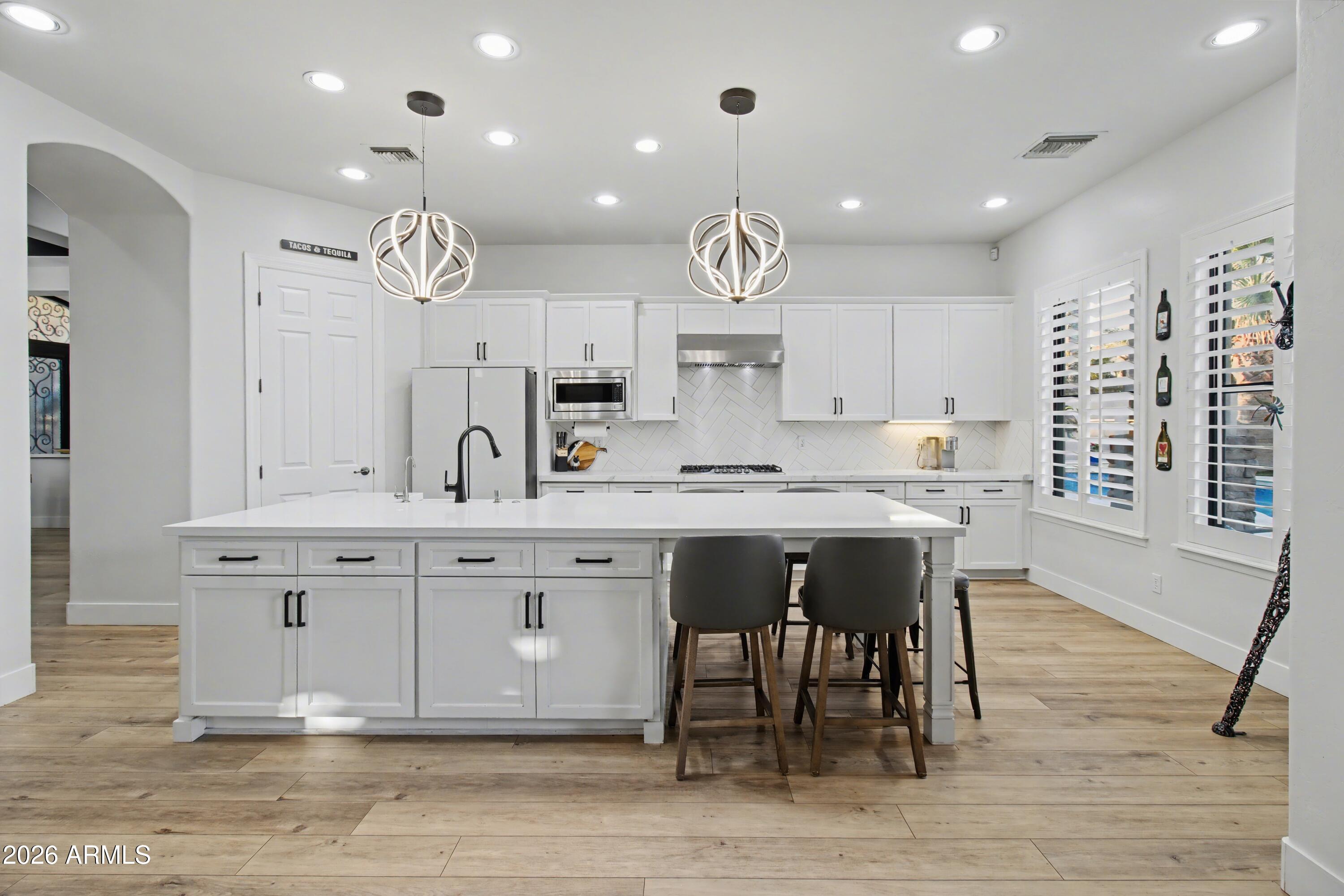 2184 West Weatherby Way Chandler, AZ 85286 - Photo 9 of 60 a kitchen with kitchen island stainless steel appliances a table chairs sink and cabinets