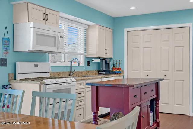 a kitchen with stainless steel appliances granite countertop a refrigerator a stove a sink and a dining table with wooden floor