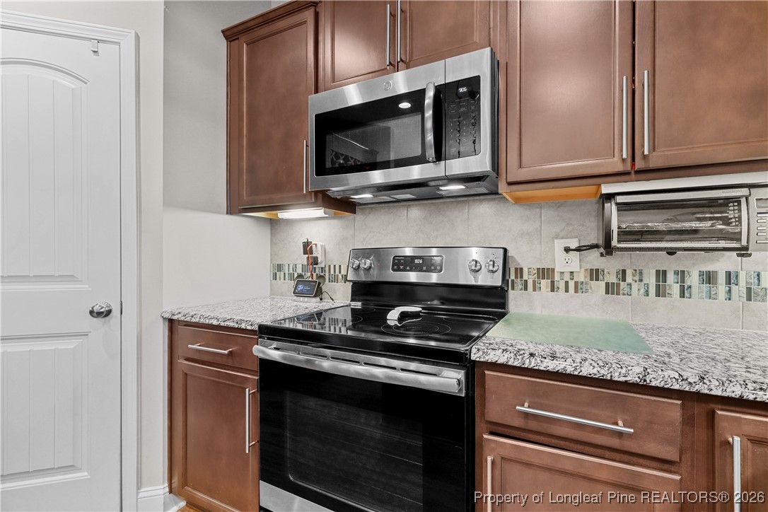 1908 Sweetfern Place Aberdeen, NC 28315 - Photo 11 of 46 a kitchen with stainless steel appliances granite countertop a stove microwave and cabinets