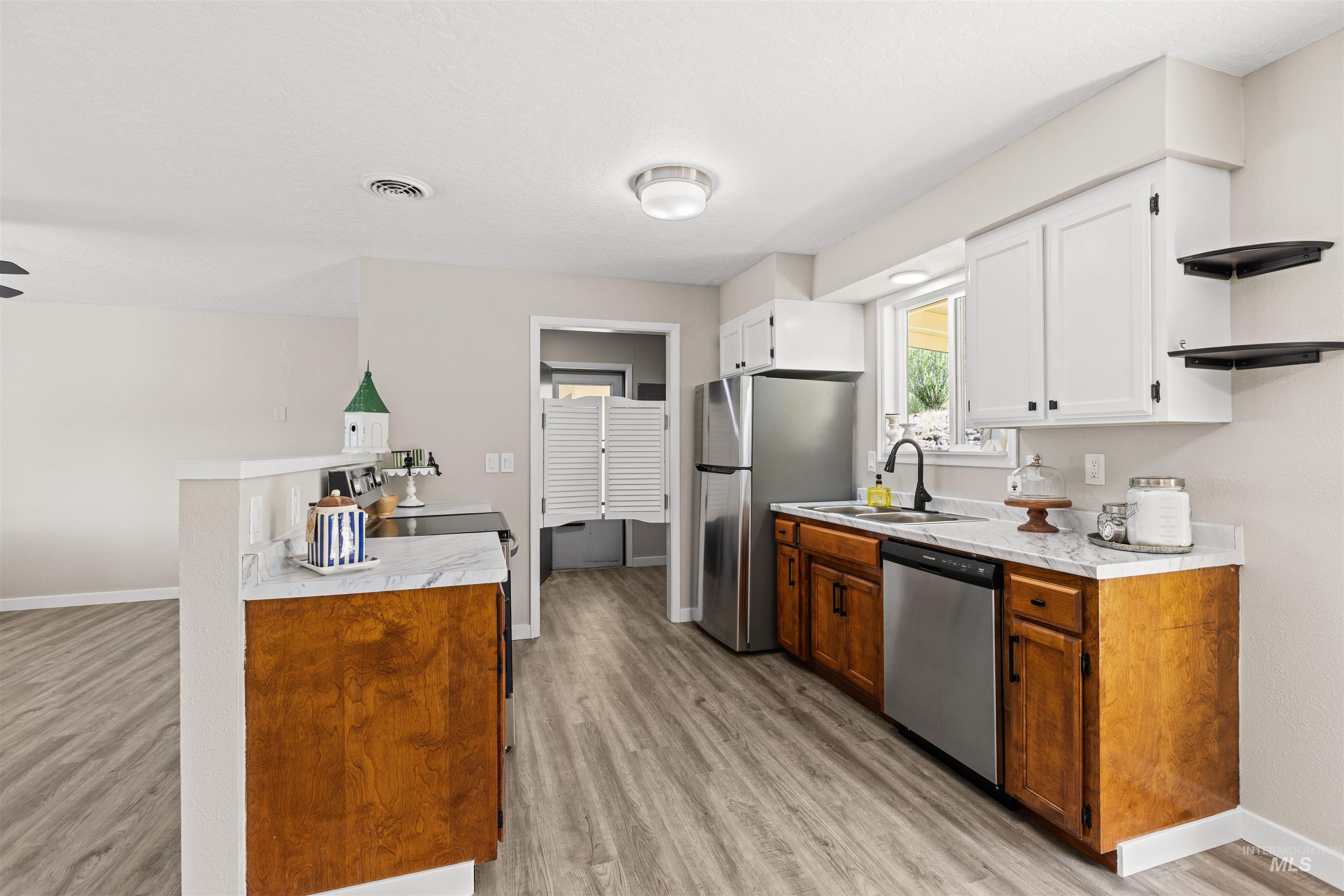 12184 Hill Road Payette, ID 83661 - Photo 14 of 35 Contemporary kitchen featuring wood-finish lower cabinetry, white upper cabinetry, and a light-toned countertop
