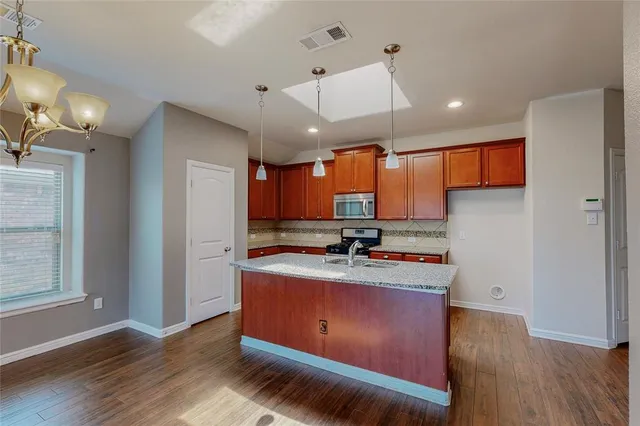 a kitchen with stainless steel appliances granite countertop a sink a stove and a wooden floors