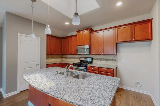 a kitchen with stainless steel appliances granite countertop a sink a stove and a wooden cabinets