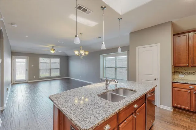 a kitchen with stainless steel appliances granite countertop a sink a oven and wooden floors