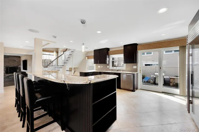 a kitchen with stainless steel appliances a sink a stove a refrigerator cabinets and chairs