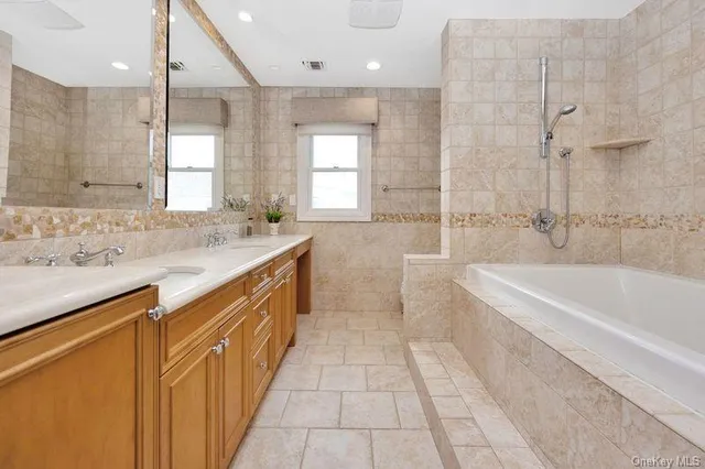 a spacious bathroom with a tub sink shower and mirror